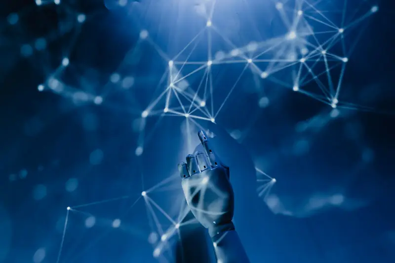 Mano robótica que toca una red de puntos luminosos sobre fondo azul, como símbolo de la inteligencia artificial